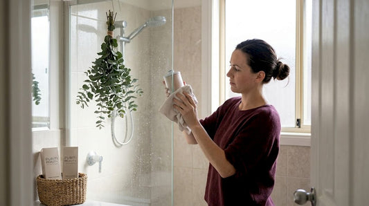 Woman cleaning shower filter in bright bathroom
